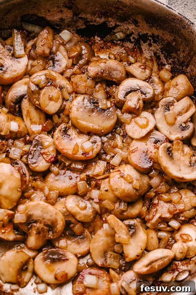 Cooking mushrooms and onions in butter in a skillet, forming the base of the mushroom gravy.