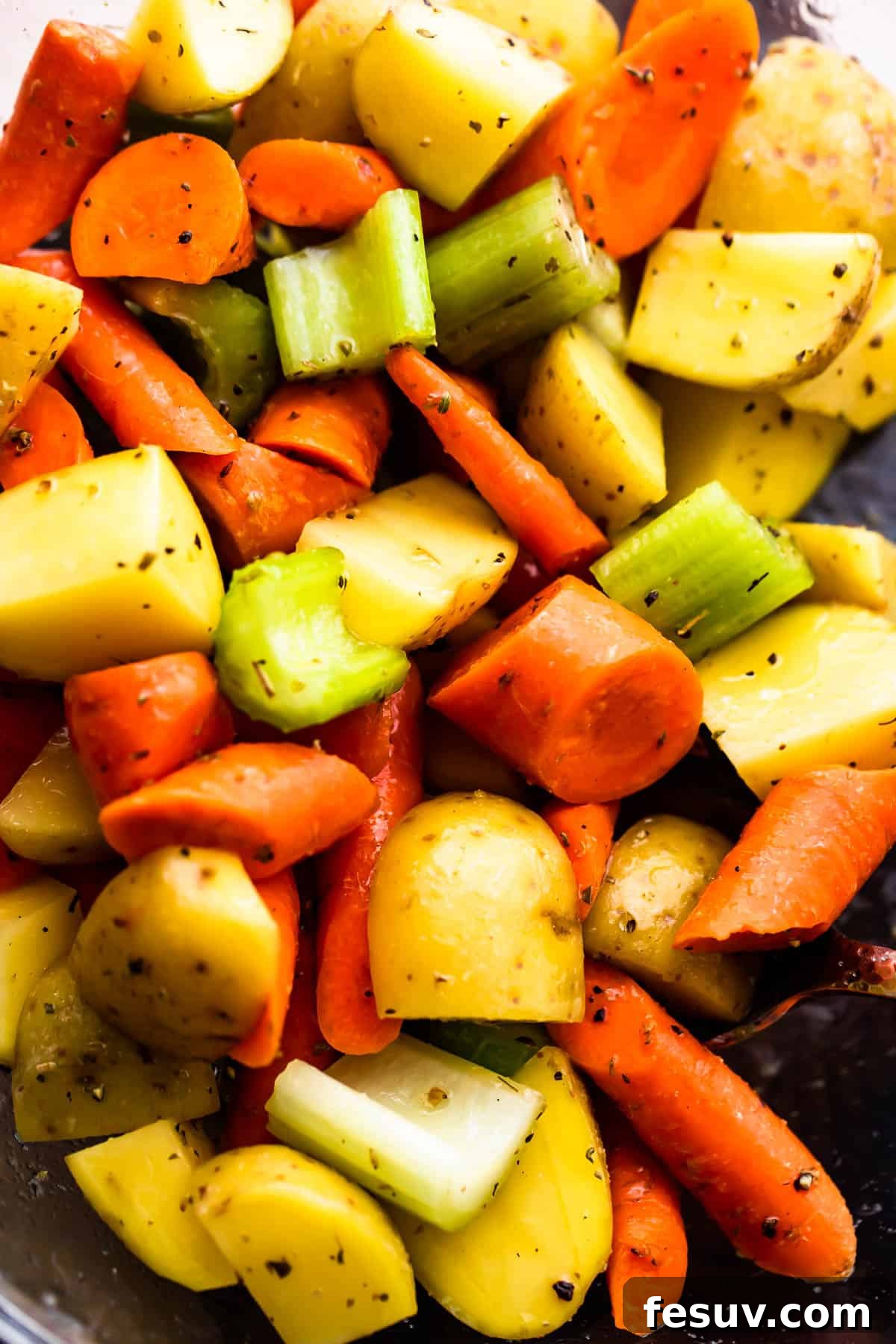Herb-Crusted Pork Loin with Roasted Root Vegetables 5 glass bowl with chopped pieces of carrots, celery, and potatoes