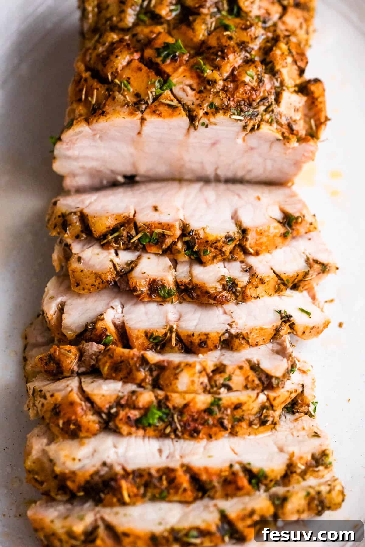 Herb-Crusted Pork Loin with Roasted Root Vegetables 6 overhead shot of cooked and sliced pork roast set on a white background