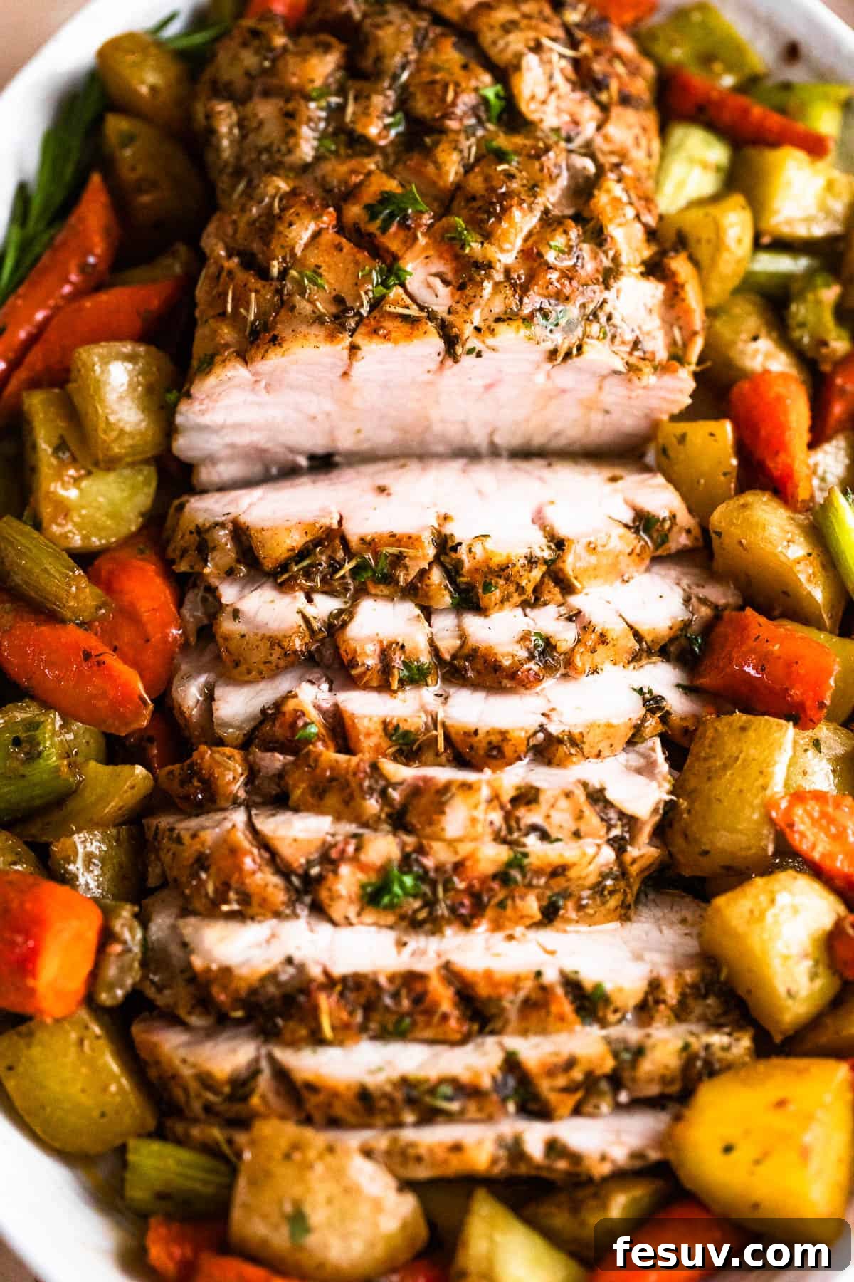 Herb-Crusted Pork Loin with Roasted Root Vegetables 8 overhead shot of oval plate with cooked and sliced pork loin roast and roasted vegetables arranged around the roast