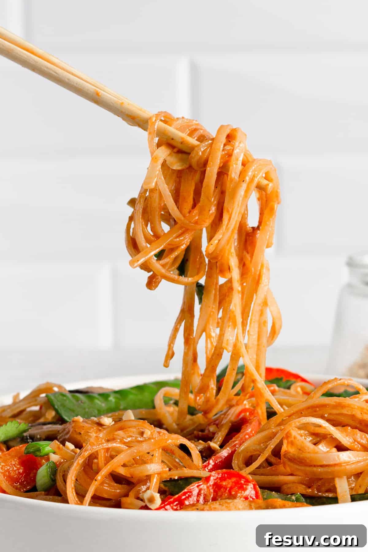 Flavorful Chicken Noodle Stir-Fry 8 A Pair of Chopsticks Holding a Bite of Chicken Lo Mein Over the Bowl