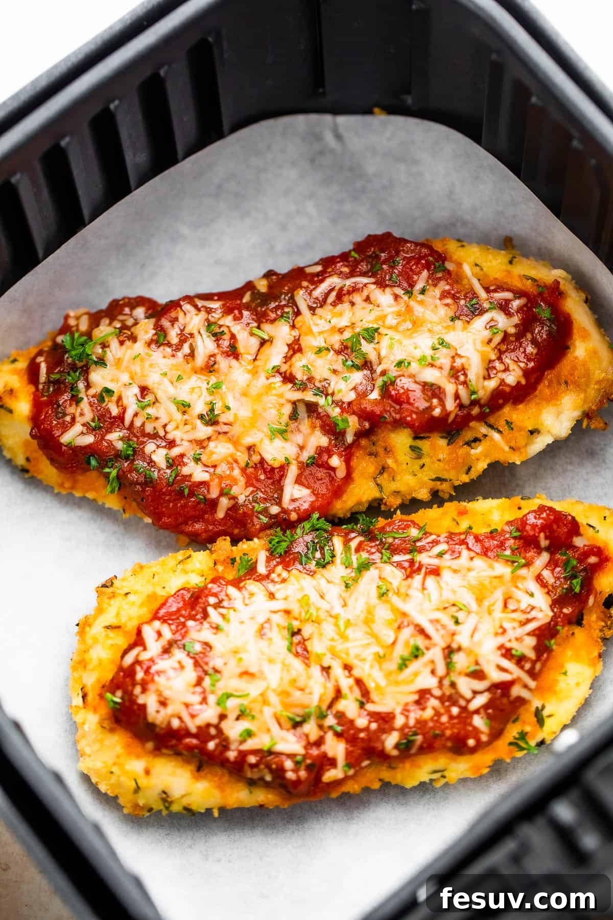 Crispy Air Fryer Chicken Parmesan 2 Two Pieces of Breaded, Partially Cooked Chicken Being Topped with Marinara and Shredded Parmesan Cheese