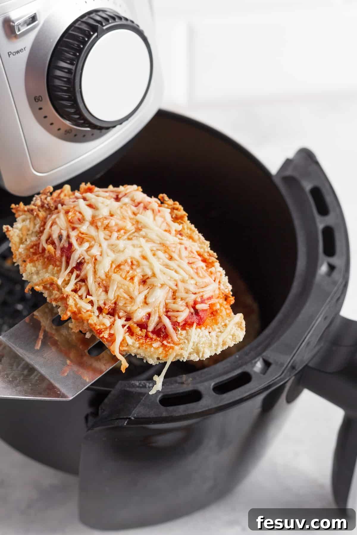 Crispy Air Fryer Chicken Parmesan 4 A Piece of Chicken Parm on a Metal Spatula Hovering Above an Air Fryer Basket