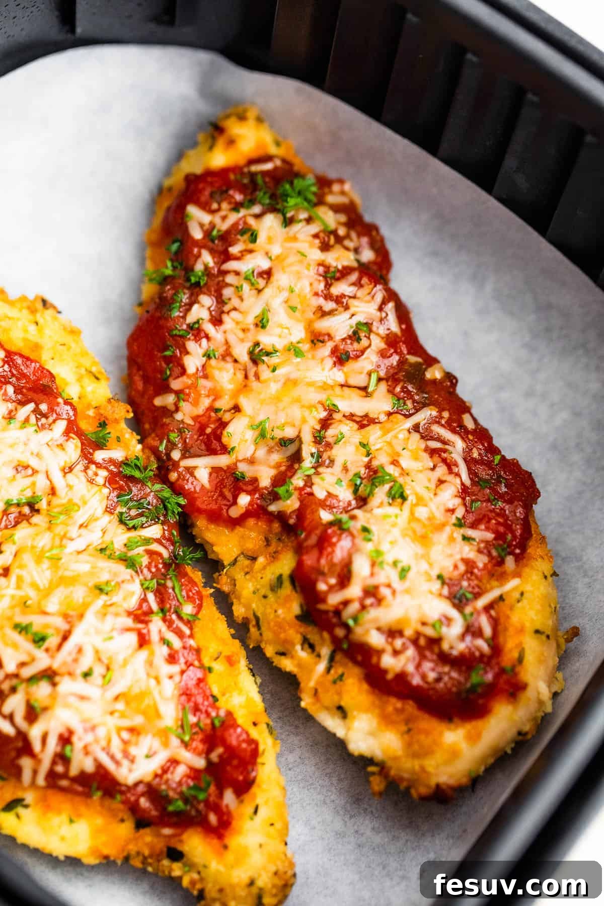 Crispy Air Fryer Chicken Parmesan 8 Two Pieces of Breaded, Partially Cooked Chicken Being Topped with Marinara and Shredded Parmesan Cheese