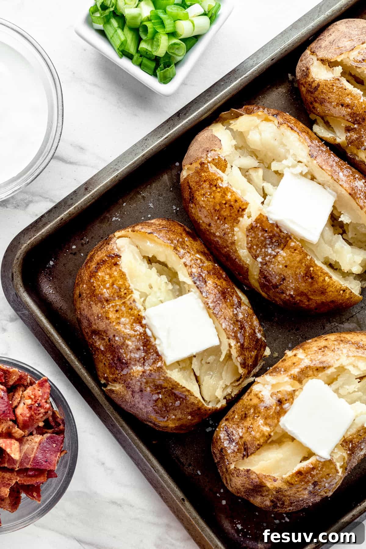 Instant Pot Baked Potatoes on a Pan with a Square of Butter on Top of Each One