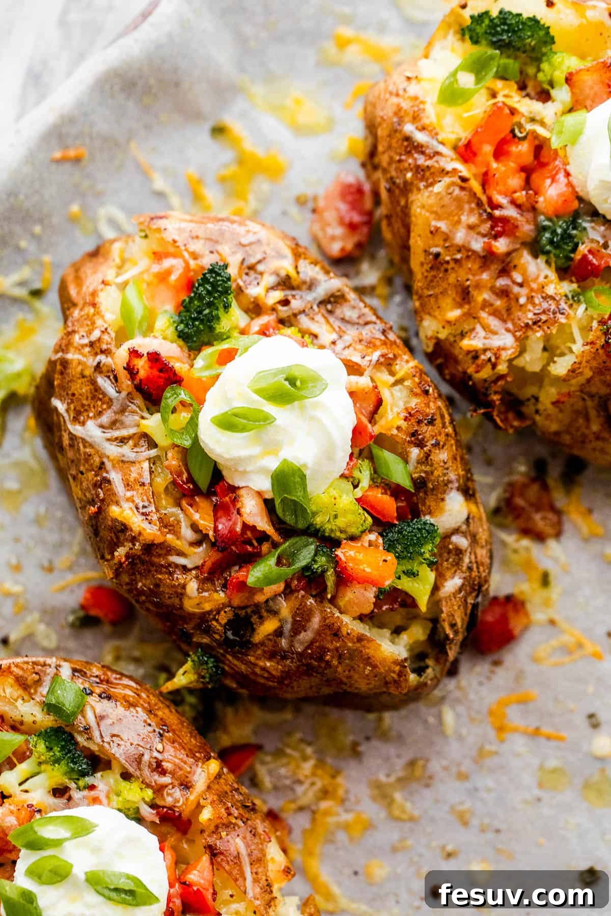 Three Instant Pot Baked Potatoes Beside Bowls of Cheese, Broccoli, Bacon, Chopped Green Onions and Sour Cream