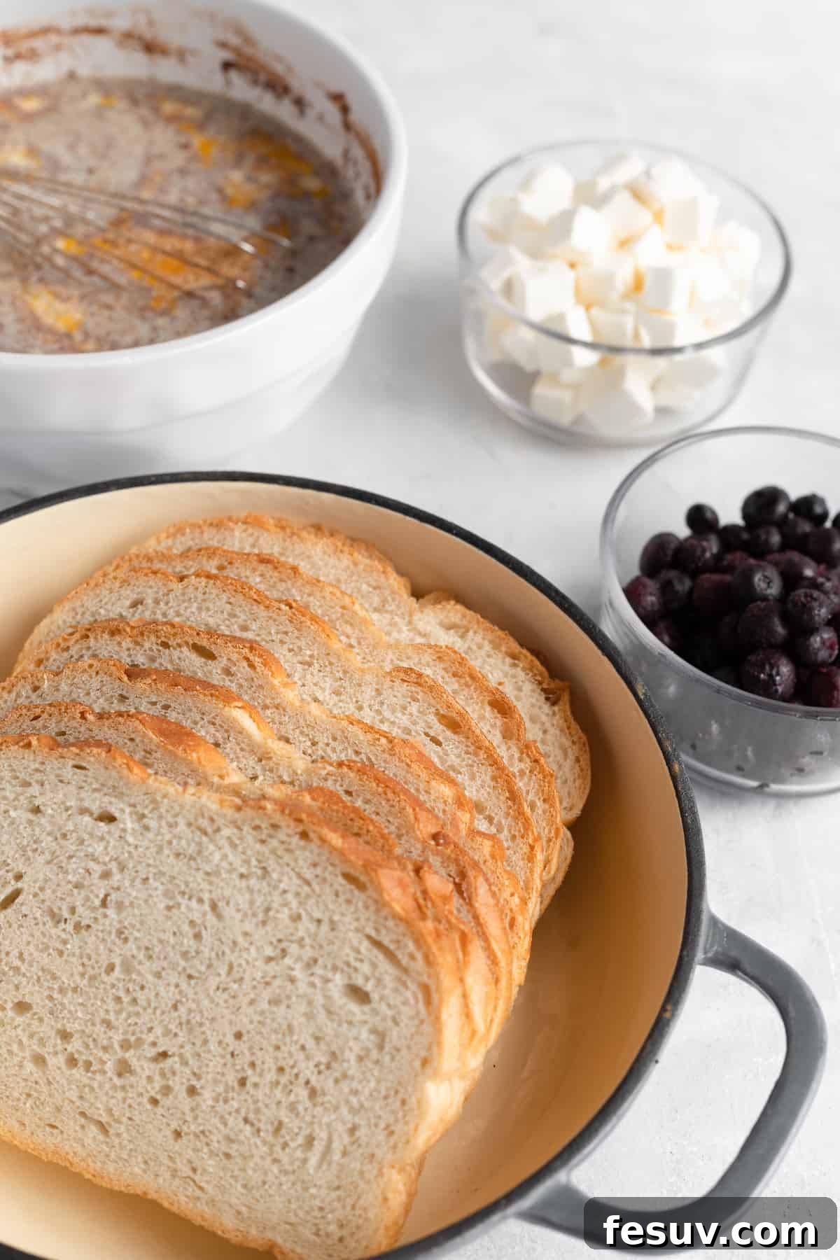 Sweet Blueberry French Toast Bake 4 Sourdough Bread, Cream Cheese Cubes, Fresh Blueberries, and Other Casserole Ingredients Neatly Arranged on a Countertop, Ready for Preparation