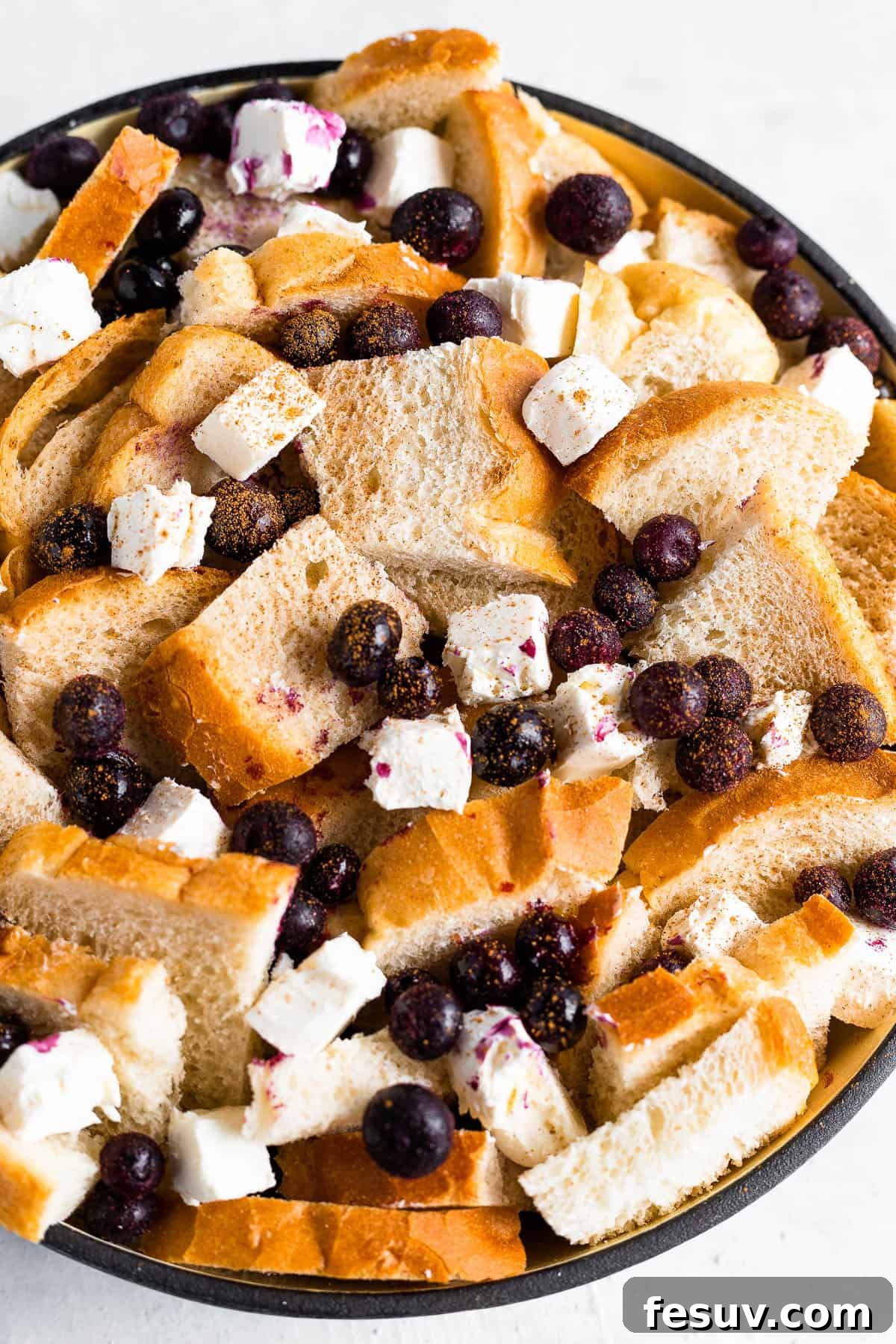 Sweet Blueberry French Toast Bake 5 Cubed Sourdough Bread, Fresh Blueberries, and Cream Cheese Cubes Artfully Arranged in a Black Baking Dish