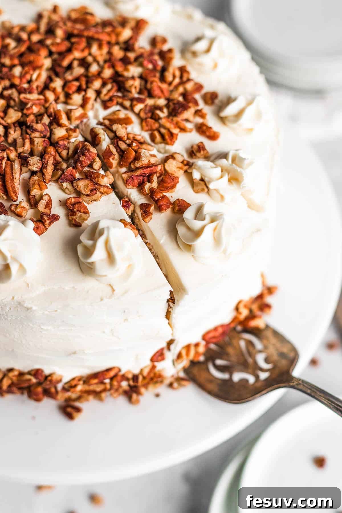 A dessert spatula gently lifting a perfect piece of Hummingbird Cake, showcasing its moist texture and creamy frosting.