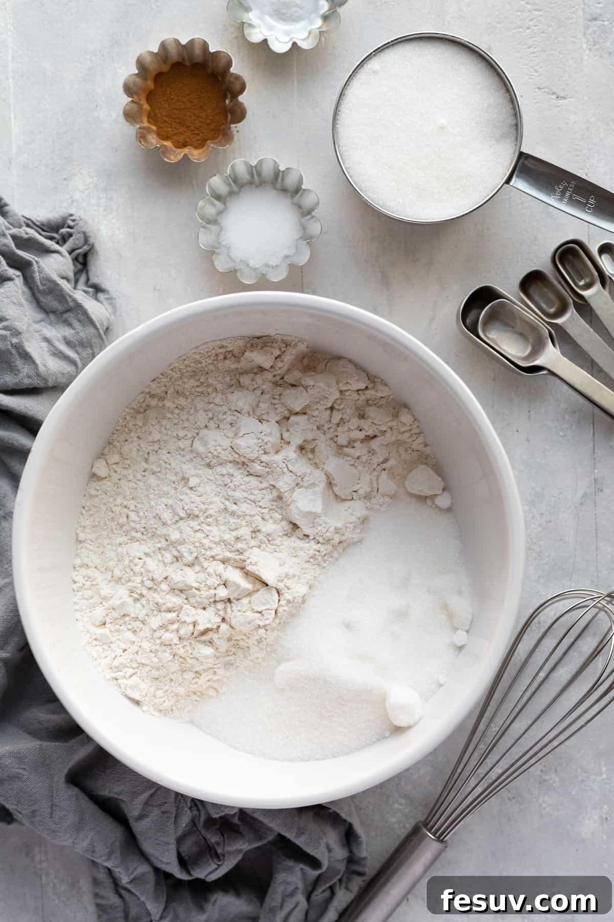 A selection of dry ingredients for Hummingbird Cake, including flour, sugar, cinnamon, and salt, artfully arranged on a countertop.