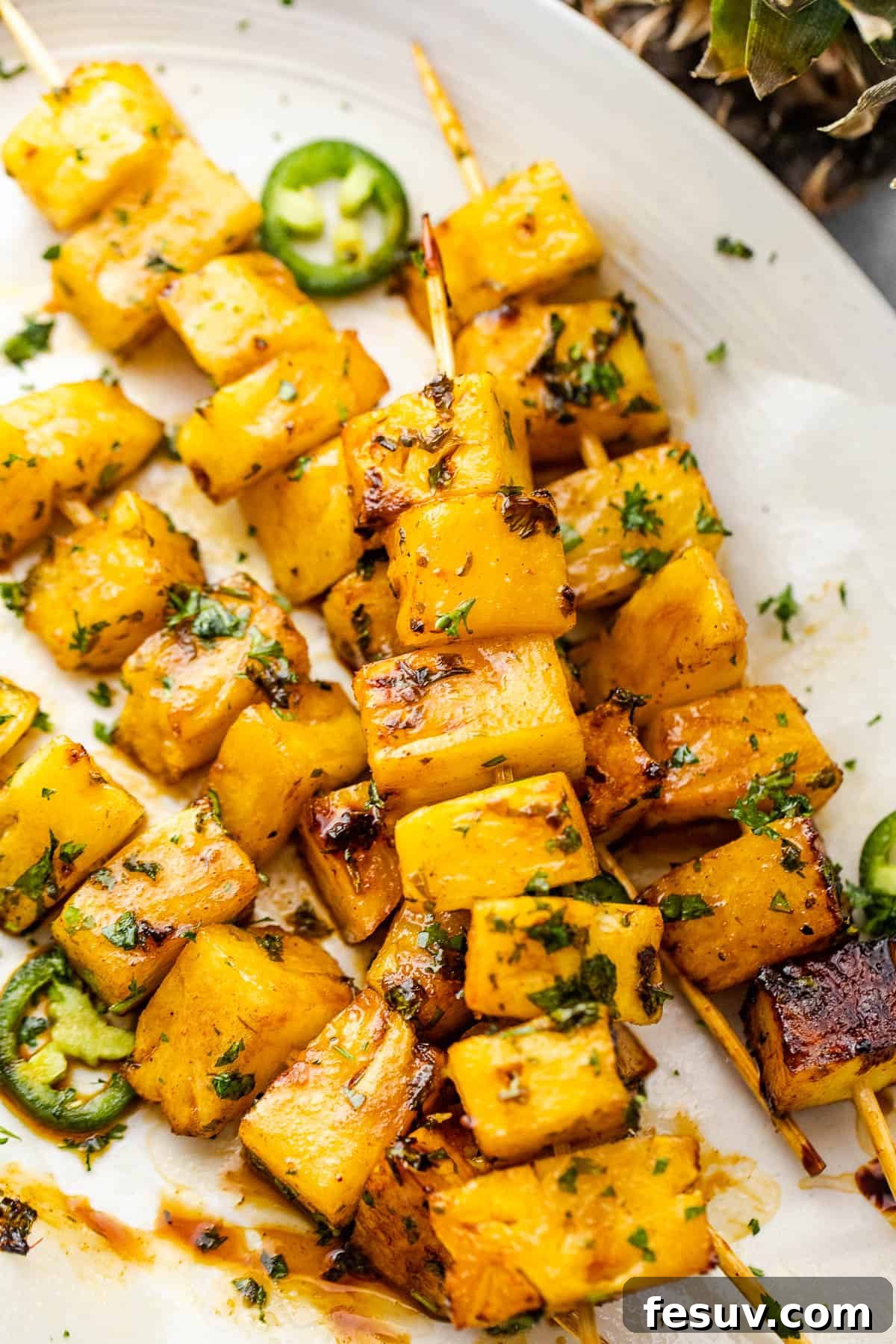 Tequila-Kissed Grilled Pineapple 2 grilled tequila pineapple skewers served on a plate