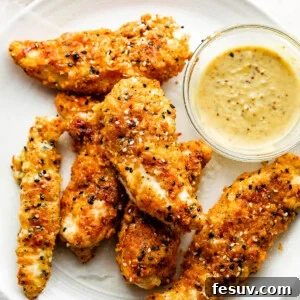 Everything Bagel Chicken Tenders arranged on a round plate and served with honey mustard dipping sauce