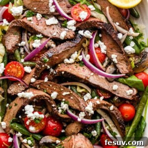 Steak Salad served on a long plate topped with cheese crumbles, tomatoes, and mushrooms