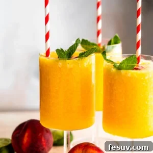 three glasses filled with peach daiquiris and garnished with mint, peach slices, and straws