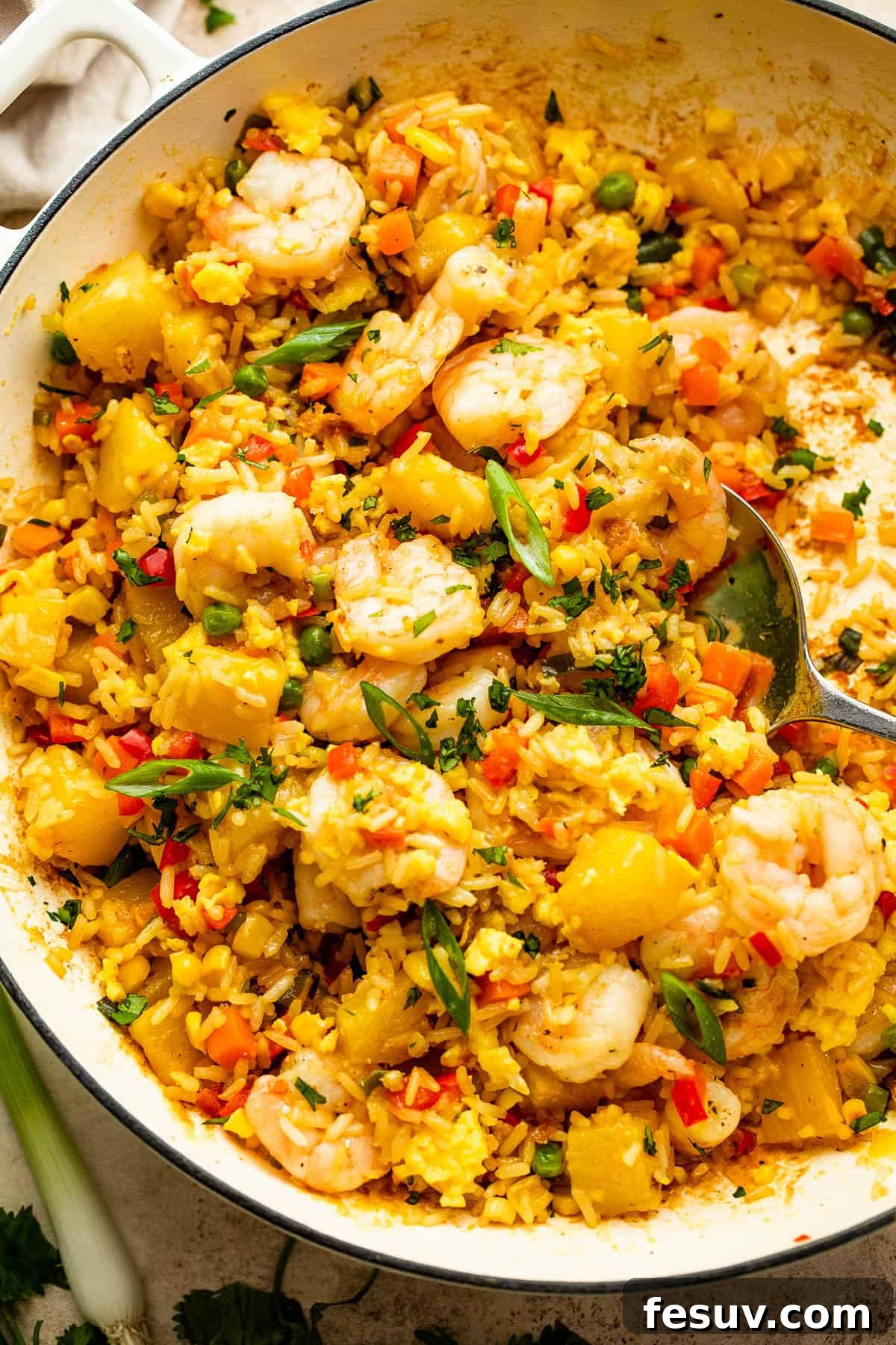 Tropical Pineapple Shrimp Fried Rice 2 White cast iron skillet with freshly cooked Shrimp Fried Rice and pineapple chunks, garnished with green onions.