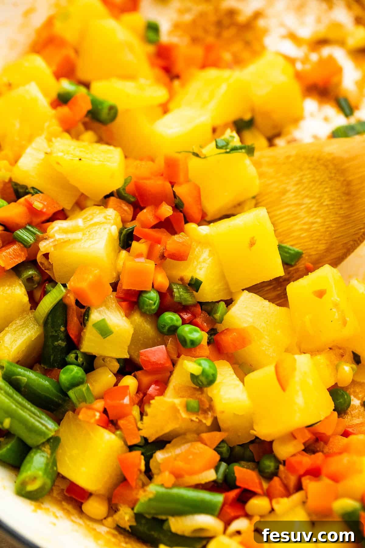 Tropical Pineapple Shrimp Fried Rice 5 Close-up of pineapple chunks being cooked with other vegetables in a wok for shrimp fried rice.