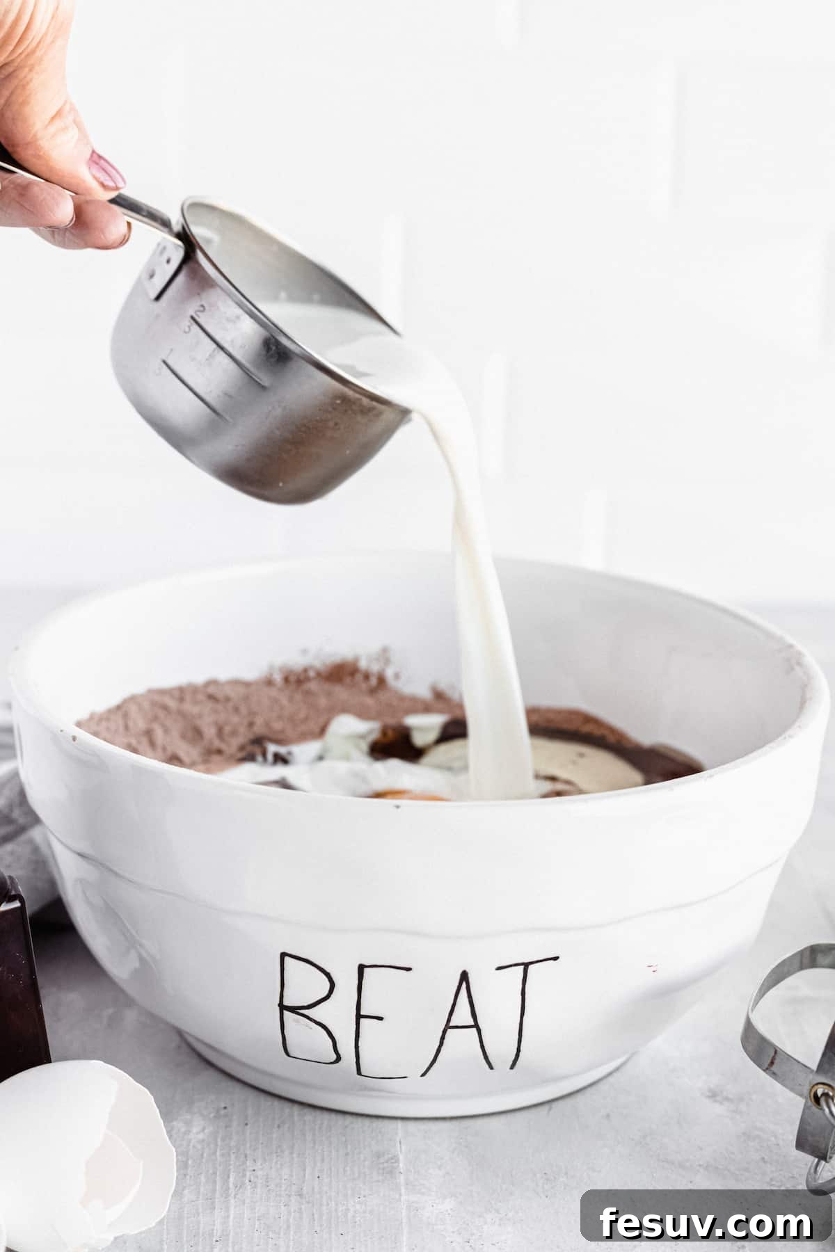 Milk being poured into a bowl of cake ingredients
