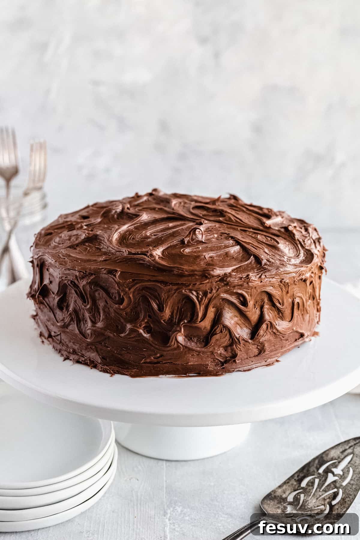 A beautifully frosted chocolate cake on a white cake stand