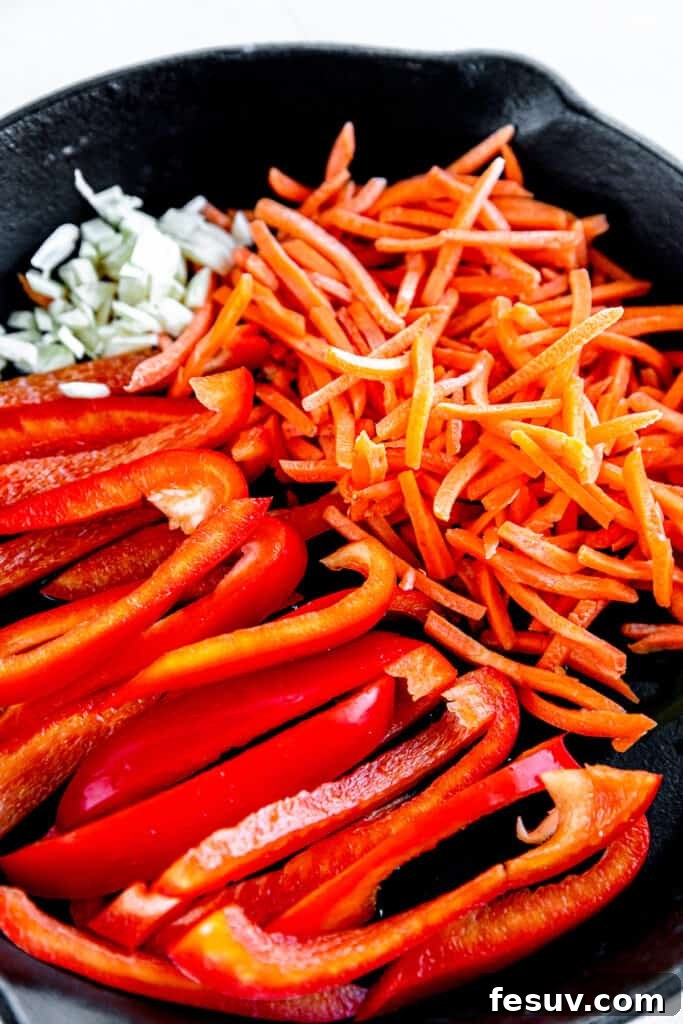In this easy Pad Thai recipe, rice noodles are tossed with scrambled eggs, roasted peanuts, colorful veggies, and a sweet, salty, sour sauce. Raw Bell Peppers, Bean Sprouts and Shredded Carrots in a Skillet