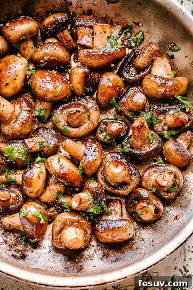 Garlic butter mushrooms expertly cooked in a skillet. A close-up shot of garlic butter mushrooms in a skillet, glistening with butter and fresh parsley.