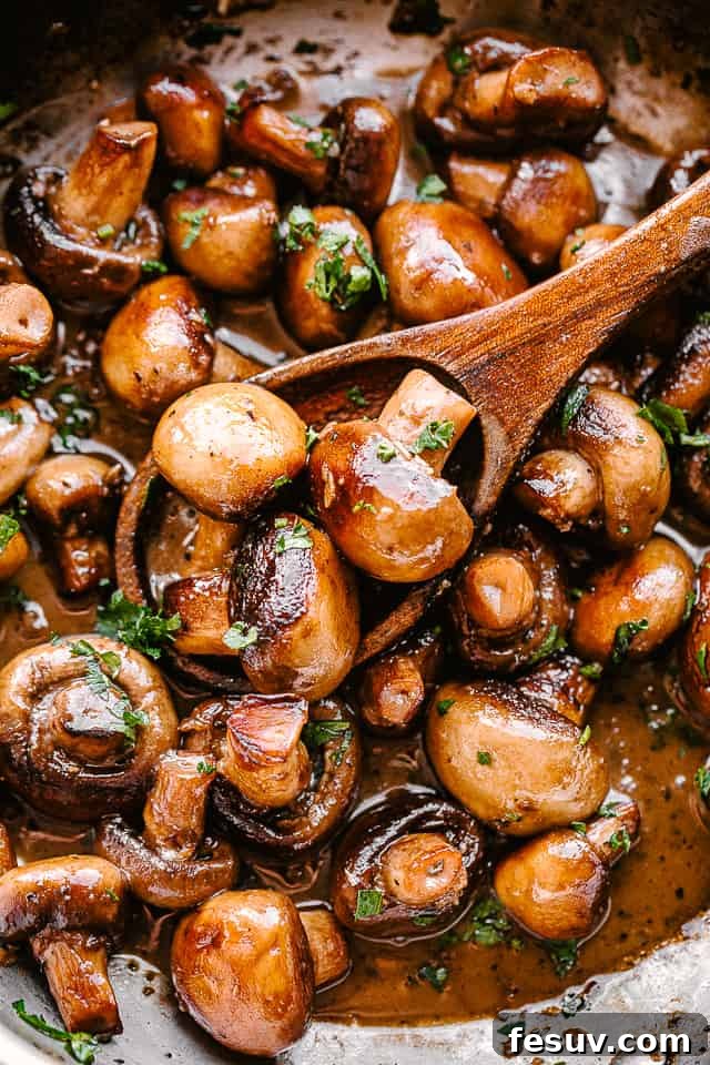 A skillet full of delectable garlic butter mushrooms. A full pan of glistening garlic butter mushrooms, garnished with fresh parsley, ready to be served.