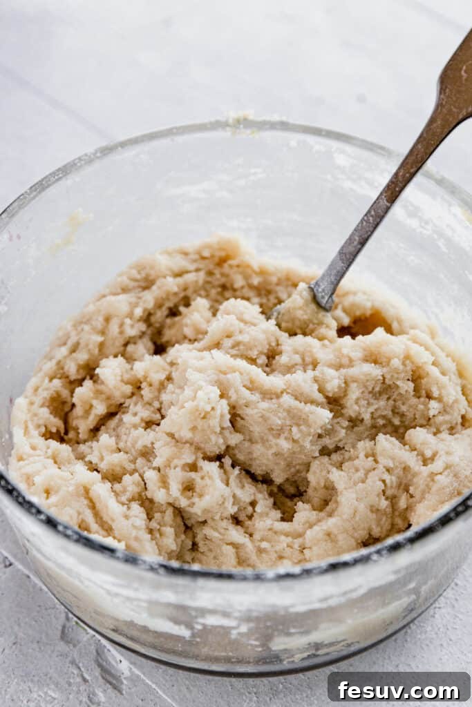 The Dough for the Topping of the Crisp in a Glass Bowl with a Metal Spoon