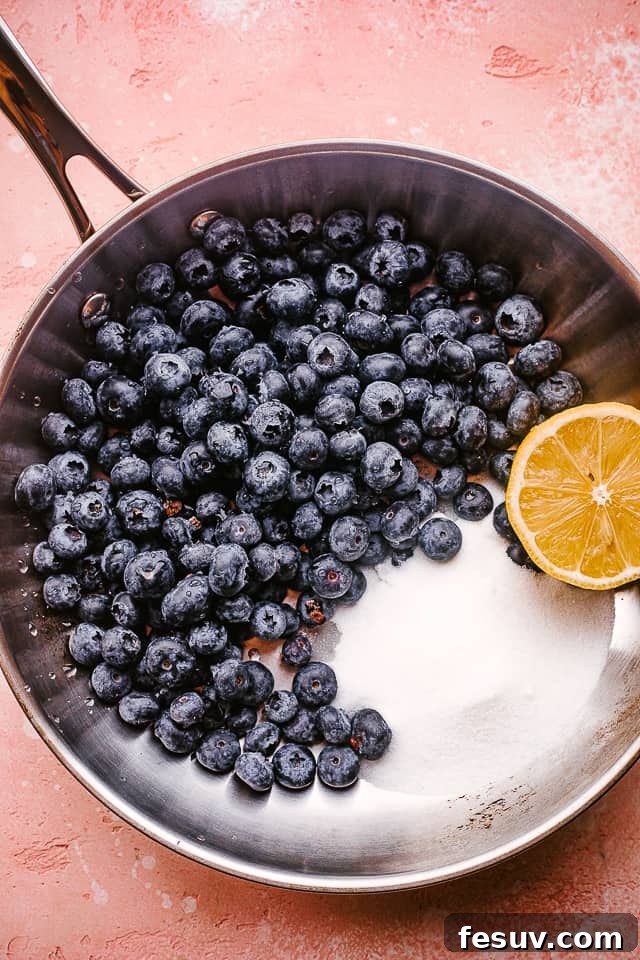 This easy blueberry sauce recipe is the perfect topping. Serve it over cheesecake, on waffles, mix it into yogurt, or spoon it onto ice cream! All the essential ingredients for blueberry sauce neatly arranged and combined in a nonstick pan, ready for cooking.
