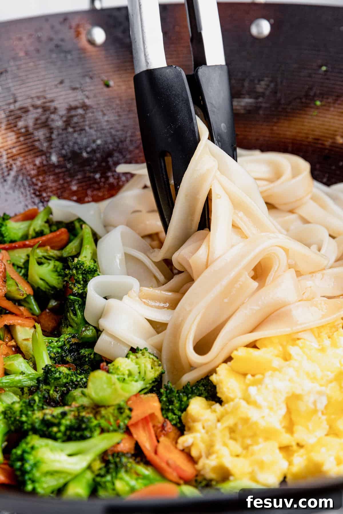 Thai Wide Noodle Perfection 8 A Pair of Tongs Mixing the Noodles with the Eggs and Vegetables