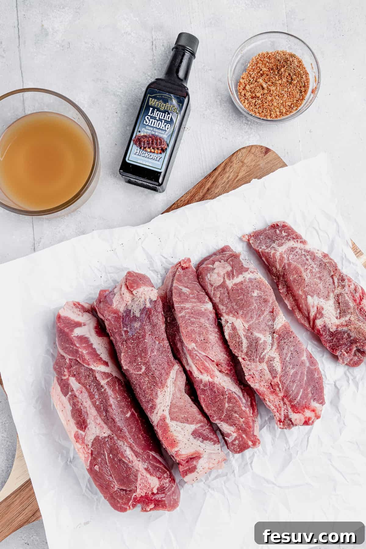 Fall-Off-The-Bone Instant Pot Ribs 4 Uncooked pork ribs, a bottle of liquid smoke, and other rib ingredients neatly arranged on a countertop