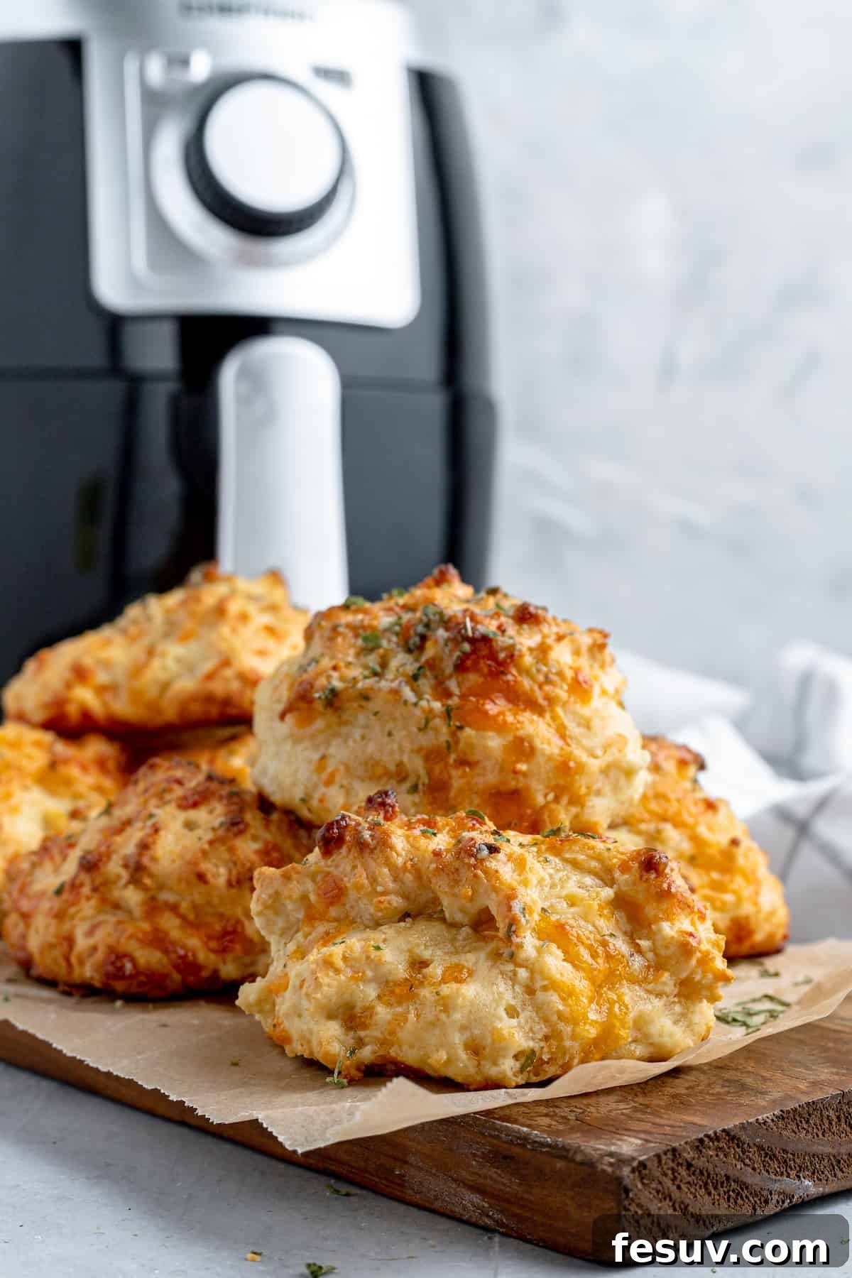 A Pile of Red Lobster Biscuits on a Cutting Board with an Air Fryer in the Background