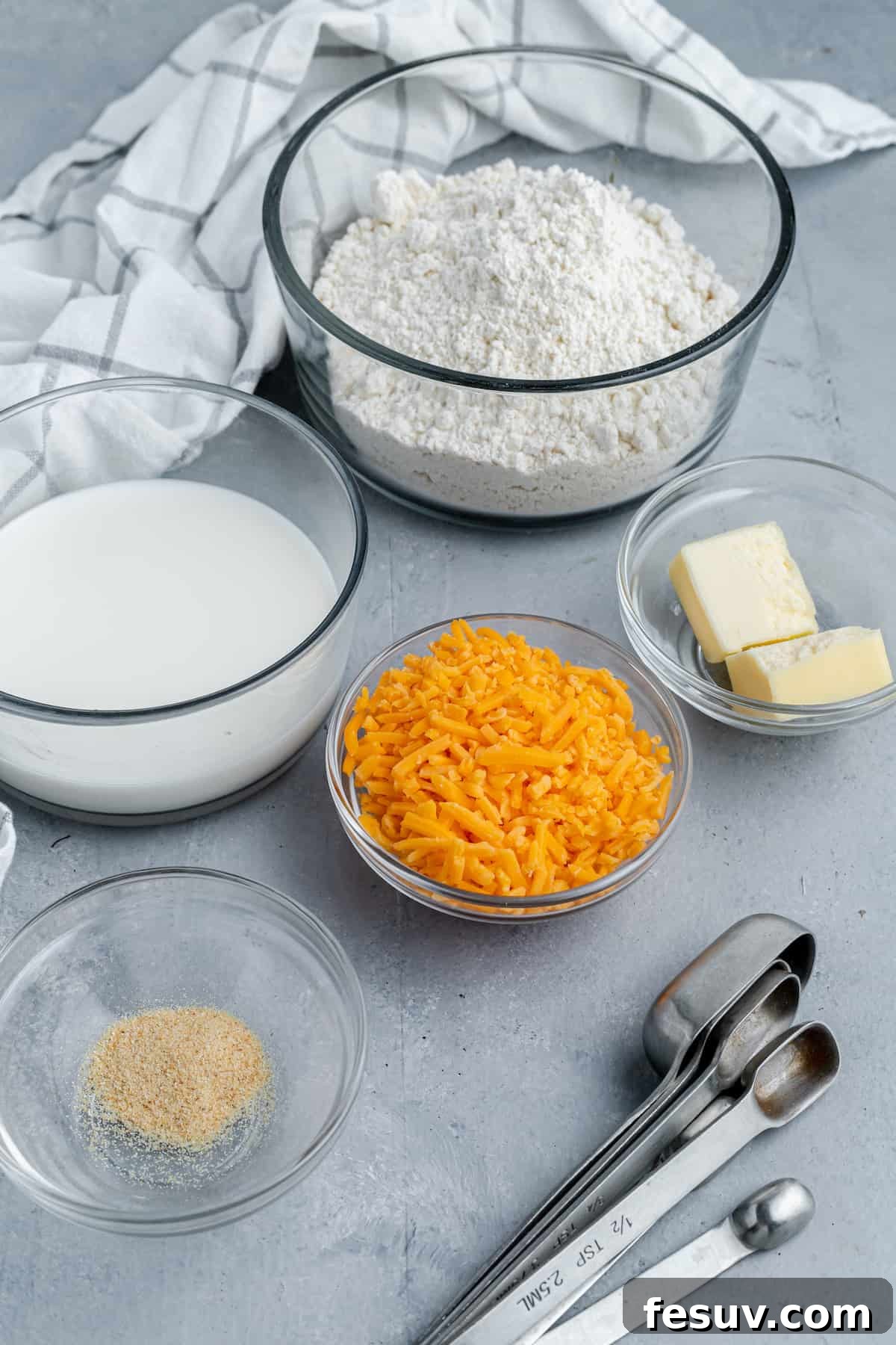Bisquick, Butter, Garlic Powder, Shredded Cheese and the Rest of the Recipe Ingredients on a Gray Countertop