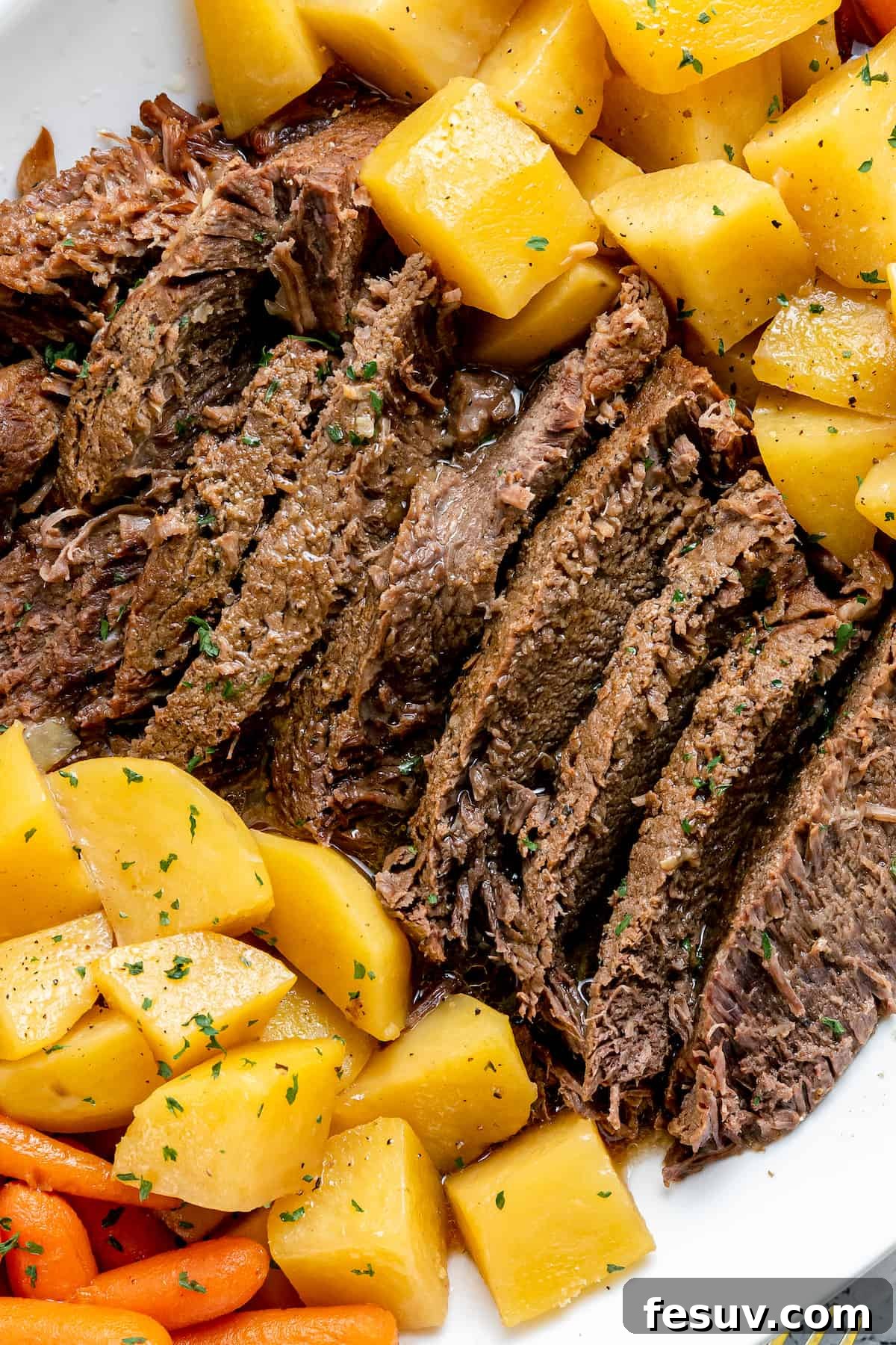 Savory Instant Pot Pot Roast with Hearty Root Vegetables 2 A perfectly cooked Instant Pot Pot Roast with tender potatoes and carrots, served on a white plate, glistening with rich jus.