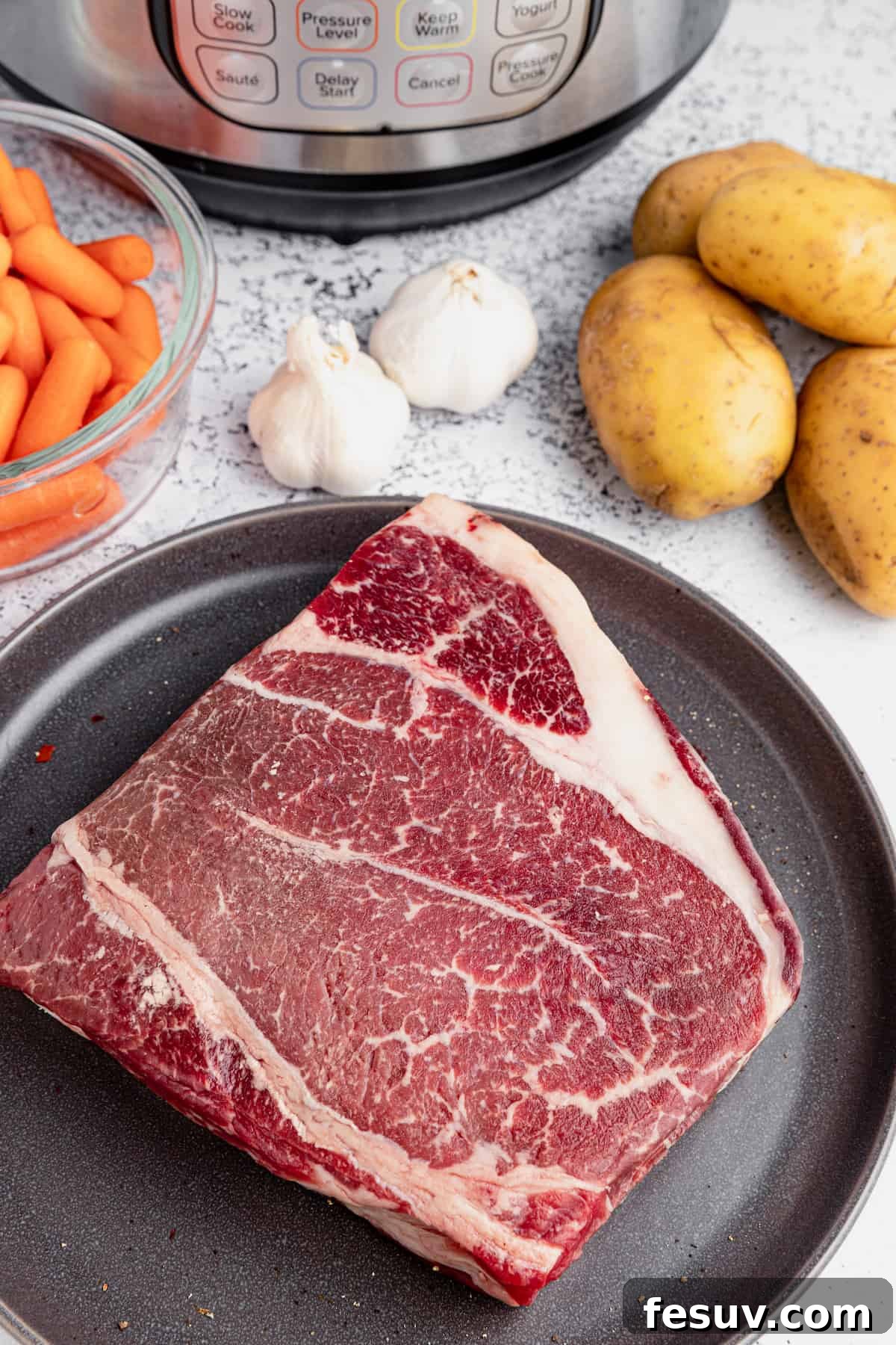 Savory Instant Pot Pot Roast with Hearty Root Vegetables 3 Close-up of raw chuck roast seasoned with spices, alongside fresh garlic cloves and vibrant carrots, ready for the Instant Pot.