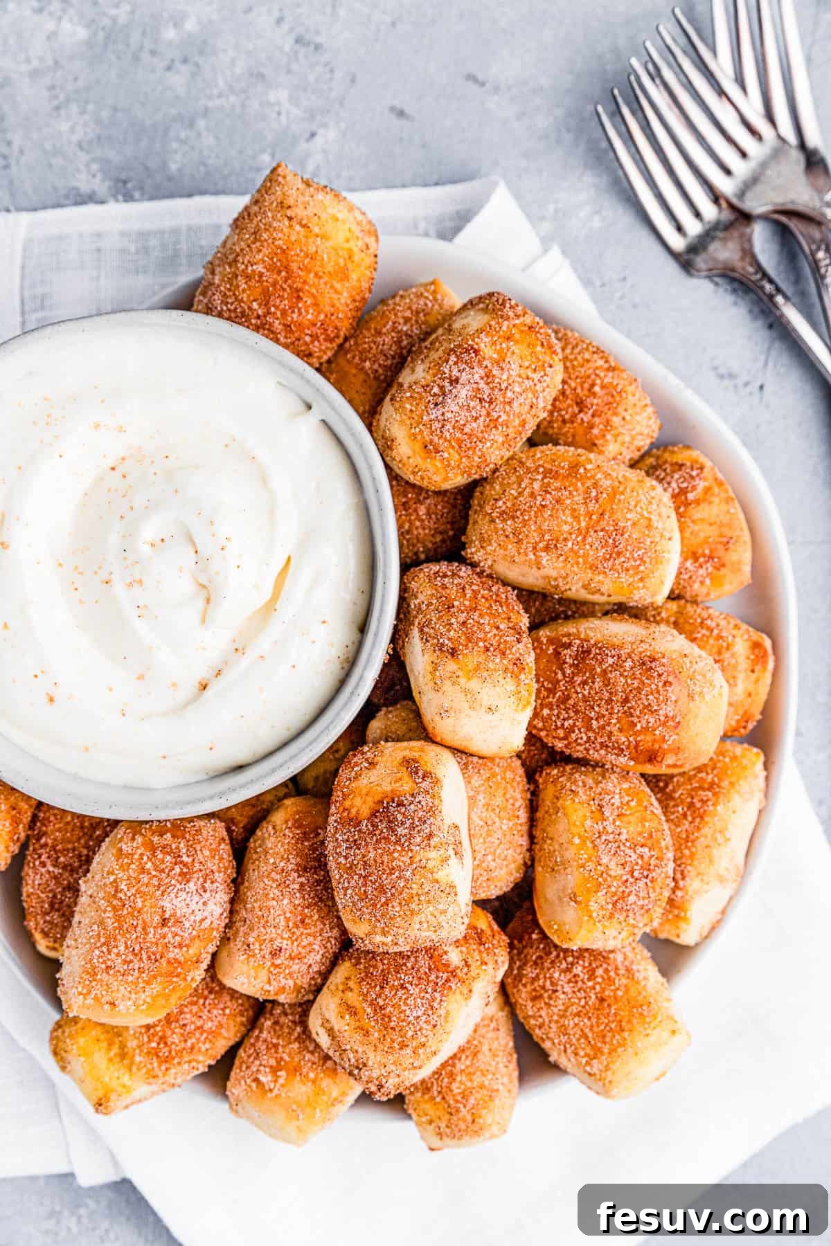 A plate of freshly baked cinnamon sugar pretzel bites with a bowl of creamy dip.