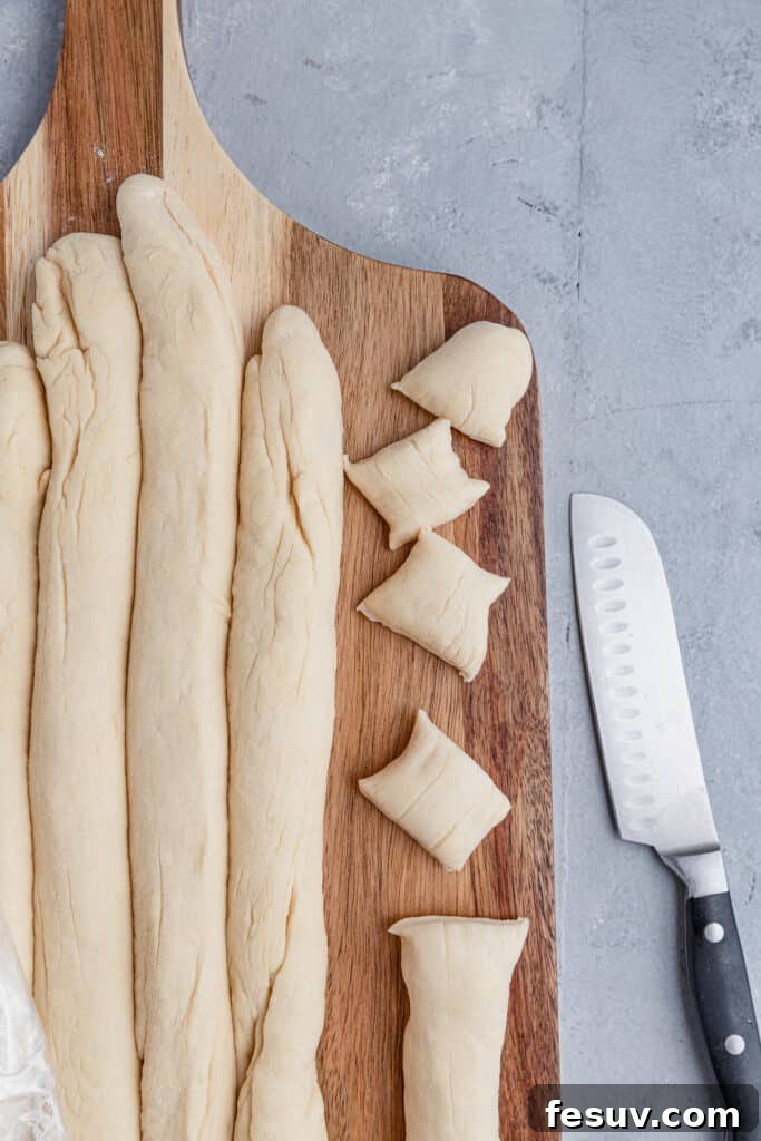 Long ropes of pretzel dough being cut into bite-sized pieces.