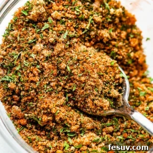Seafood seasoning blend in a small glass mixing bowl with a teaspoon inside, ready for use.