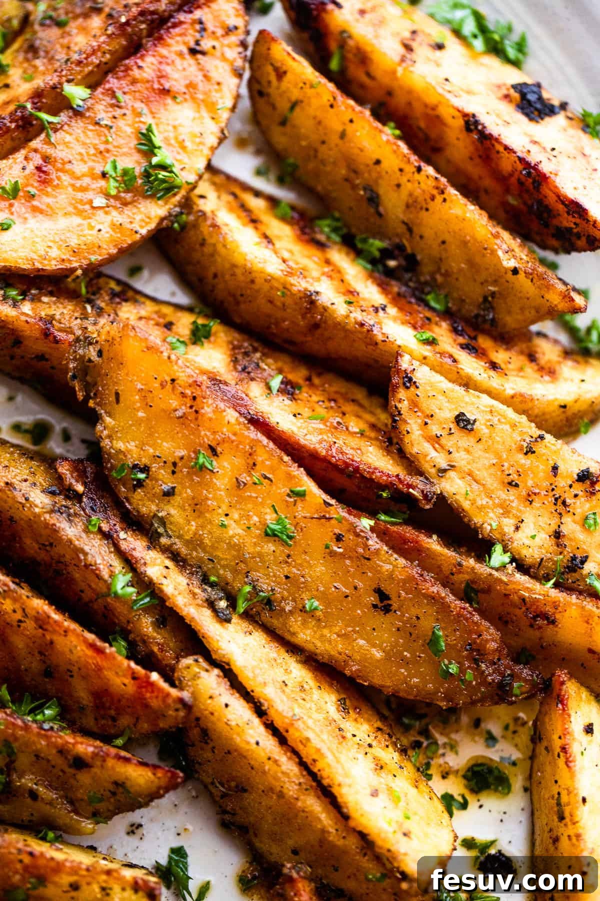 Golden-brown grilled potato wedges, perfectly seasoned and cooked. Close-up image of grilled sliced potatoes, showcasing their crispy edges and tender interior.