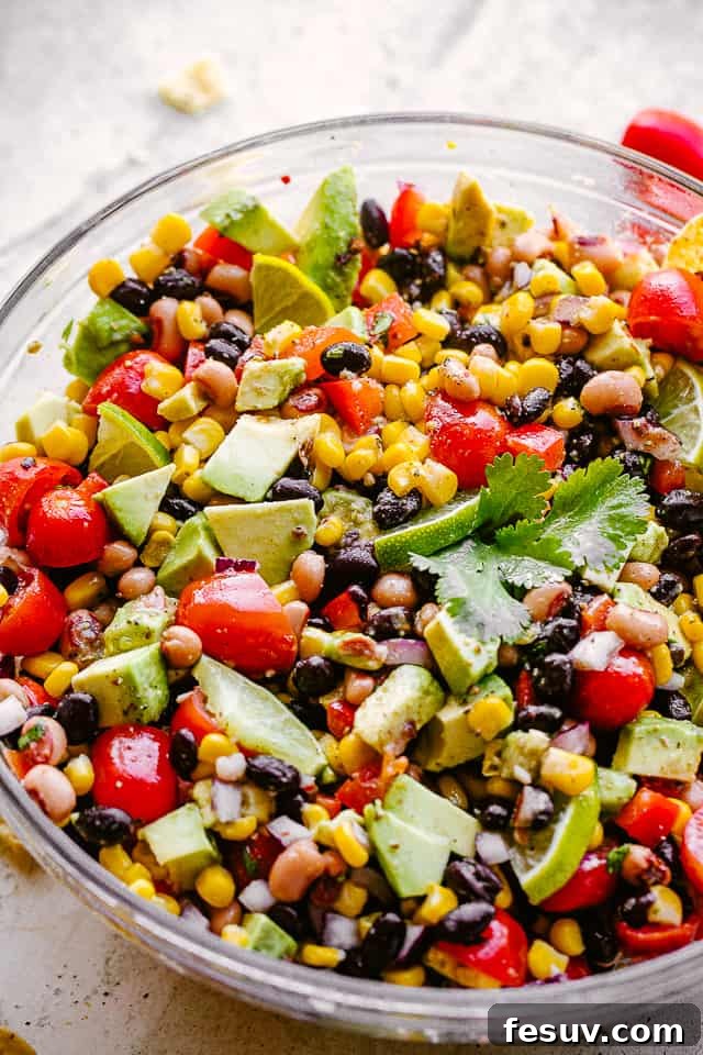 Another shot of vibrant Cowboy Caviar with avocado, corn, tomatoes, black-eyed peas, beans, and cilantro in a large glass bowl