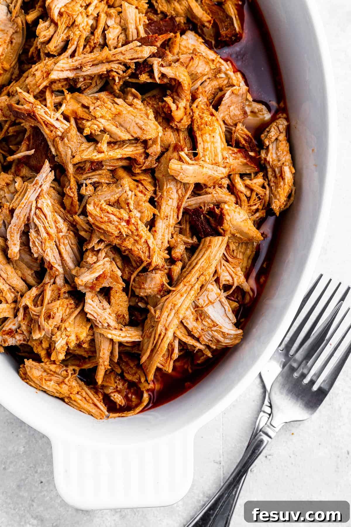 Effortless Instant Pot Pulled Pork with Zesty Coleslaw 3 Hearty serving of smoky pulled pork in a baking dish, glistening with barbecue sauce