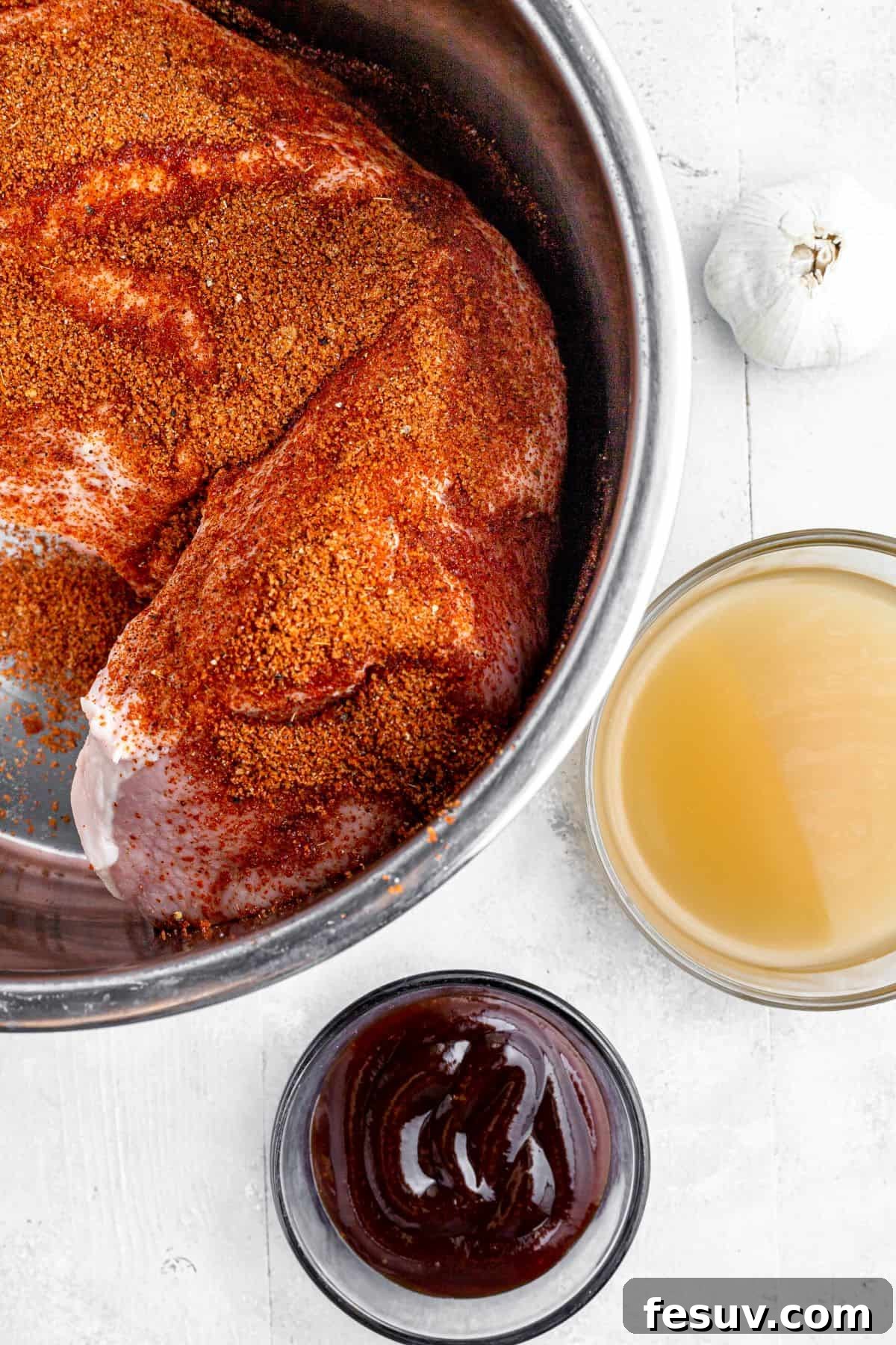 Effortless Instant Pot Pulled Pork with Zesty Coleslaw 5 Pork loin with seasoning rub inside an Instant Pot, surrounded by garlic, broth, and barbecue sauce