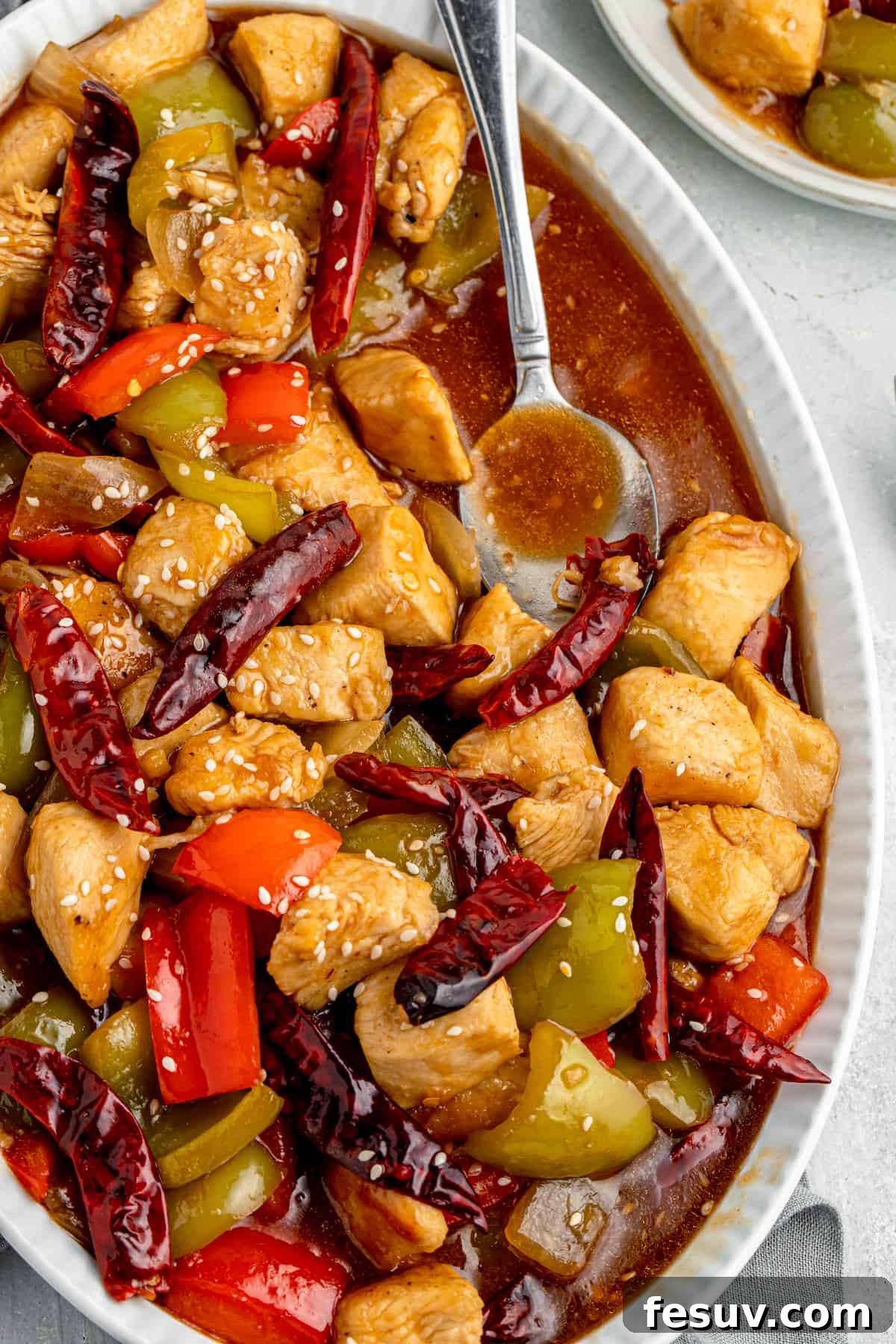 A vibrant close-up of Szechuan Chicken stir-fry, showcasing tender chicken, colorful bell peppers, and dried red chilies, all coated in a glossy, rich sauce.