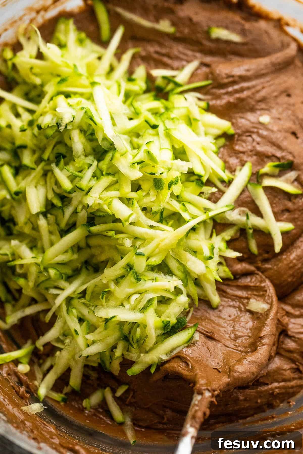 mixing shredded zucchini into a rich chocolate batter for zucchini bread