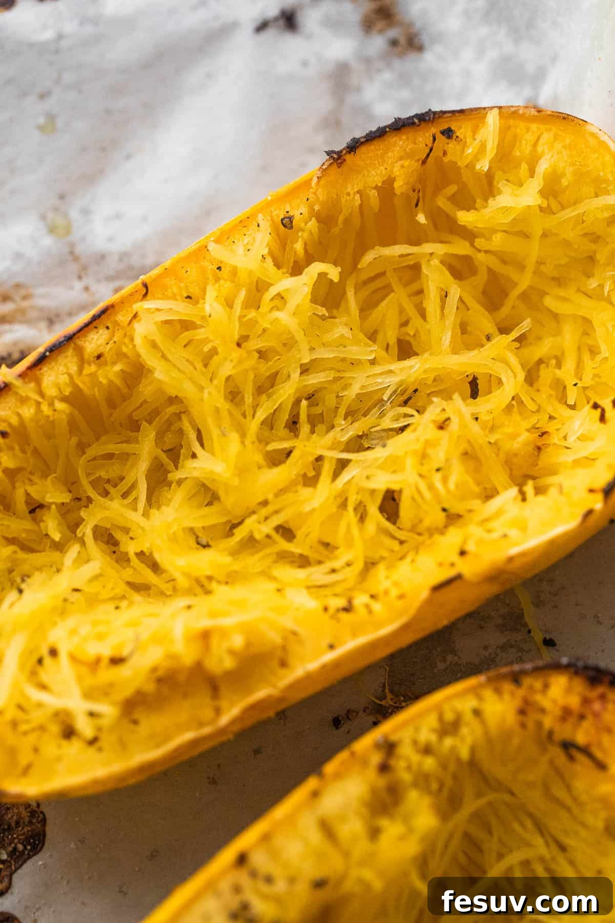 A spaghetti squash, cut in half and placed on a baking sheet, ready for roasting.