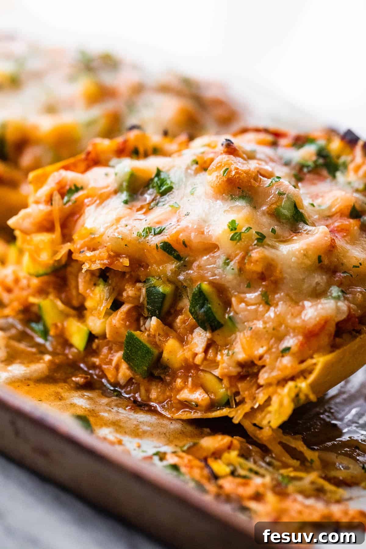 Halved spaghetti squash stuffed with chicken enchilada filling and topped with melted cheese, with fresh cilantro garnish.