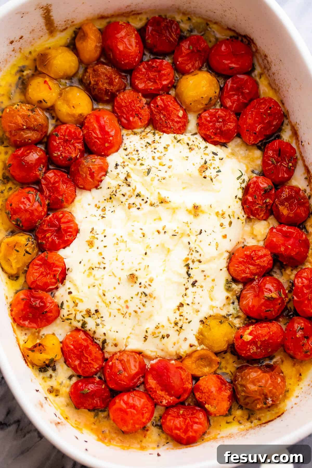 Rich Cream Cheese Shrimp Pasta Bake 4 A baking dish with a block of cream cheese surrounded by cherry tomatoes and minced garlic, ready for the oven.