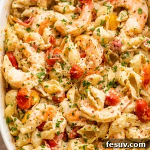 white baking dish with shrimp and pasta tossed with a cream cheese sauce and cherry tomatoes