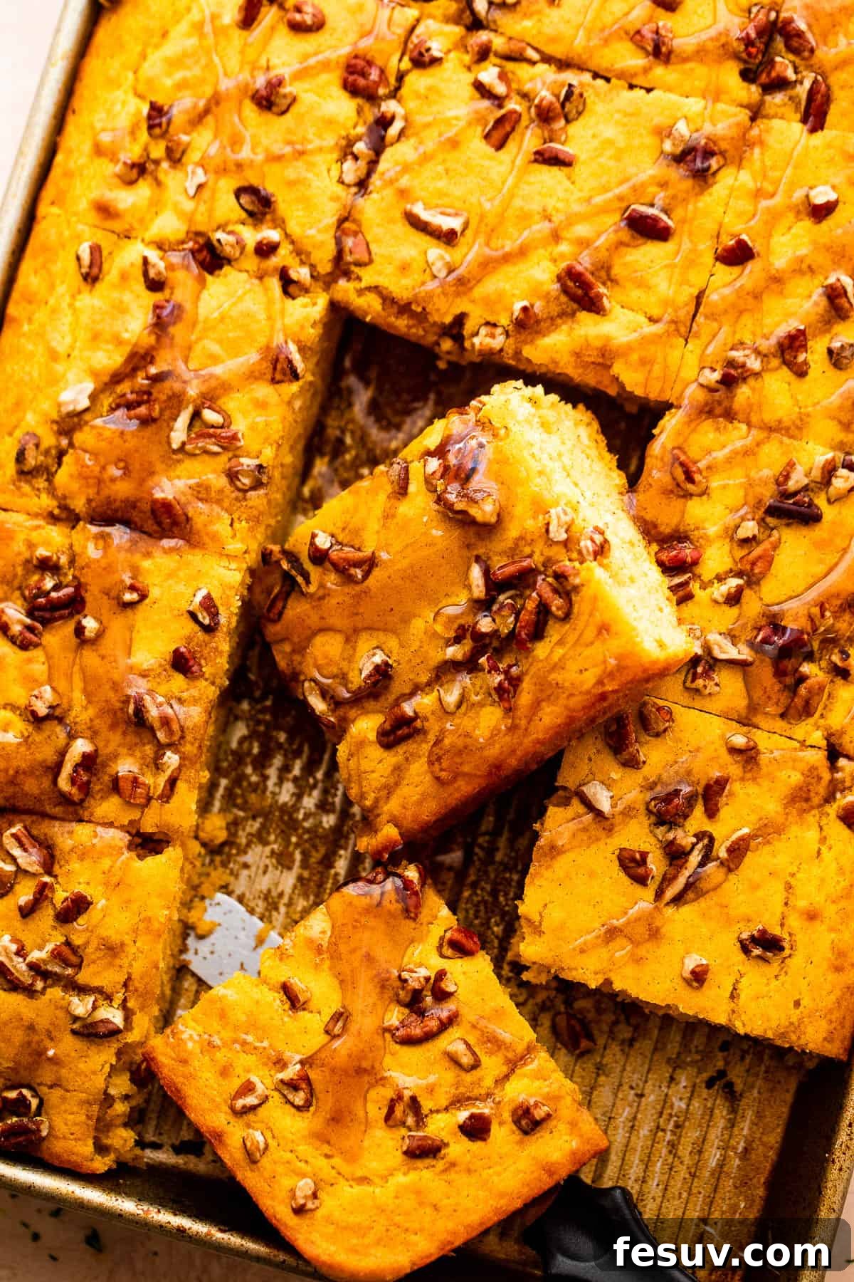 An inviting overhead shot showcasing the large, golden-brown sheet pan pumpkin pancakes, perfectly baked and ready to be cut into squares, adorned with chopped pecans.