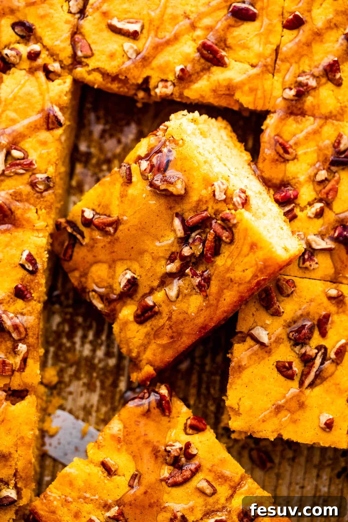 A close-up overhead shot of beautifully baked sheet pan pumpkin pancakes, cut into neat squares and garnished with a light dusting of powdered sugar, ready for serving.