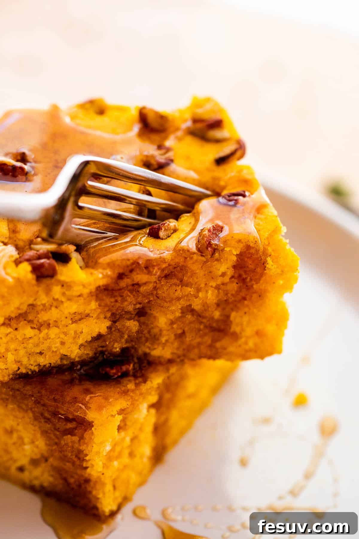 A fork piercing a soft, perfectly cooked square of sheet pan pumpkin pancake, ready to be lifted and enjoyed, emphasizing its fluffy texture.