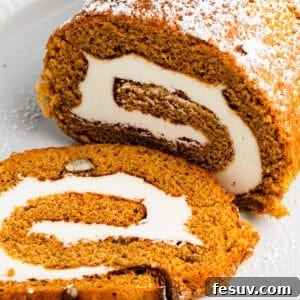 Pumpkin cake roll with one slice cut out and the filling exposed.